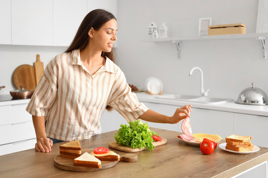 Young woman making tasty sandwich in kitchen