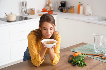 Young woman with bowl of chicken soup in kitchen
