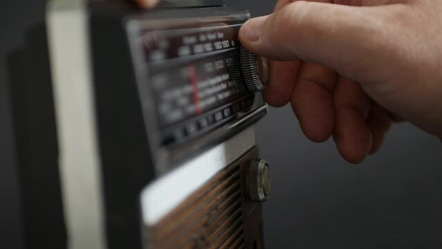 Blurred Shooting with One Person Searching a News Radio Station or a Music Radio Station Using an Old Radio. Man Searching a Broadcasting Frequency by Rotating a Radio Button.