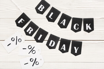 Rope, flags with text BLACK FRIDAY and percent signs on white wooden background