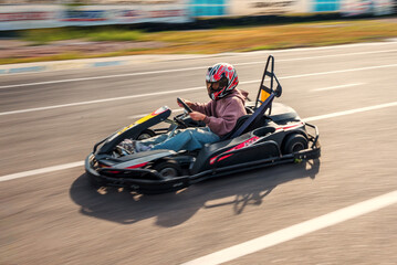 Girl racer driving a go-kart on a race track - obrazy, fototapety, plakaty