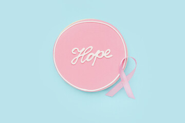 Cookie with word HOPE and pink ribbon on blue background. Breast cancer awareness concept