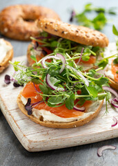 Smoked salmon and soft cheese seeded bagel with pea and purple reddish shoot salad and red onion....