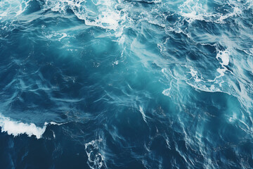 aerial perspective, the deep navy blue expanse of the ocean stretches out beneath, with white waves crashing and splashing against its surface. - obrazy, fototapety, plakaty