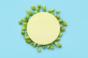 Blank card with fresh green hops on blue background