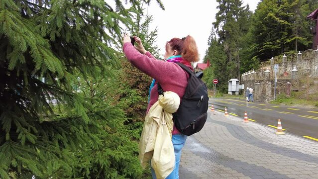 Woman with backpack takes photo with smartphone