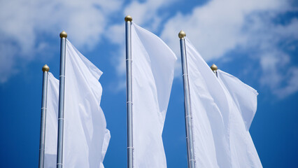 White flags waving in the wind against a blue sky with clouds