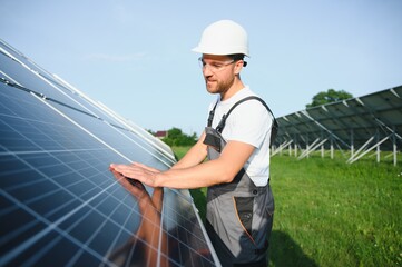 Male worker solar power plant on a background of photovoltaic panels.