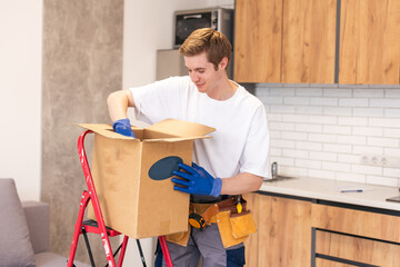 moving, people and real estate concept - happy smiling man holding boxes with stuff at new home