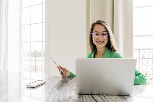 A company finance employee uses a chatbot for work. A professional woman in the field of marketing works using a laptop and tablet. A young specialist person prints online texts for a blog. - Powered by Adobe