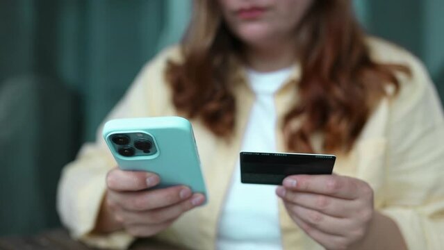 Online shopping. Female hands holding a smartphone and a credit card over blurred background. Credit card payment, mobile banking.