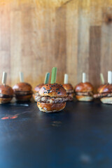 Close-up of mini burgers with a wooden toothpick ready for a party snack.Front view