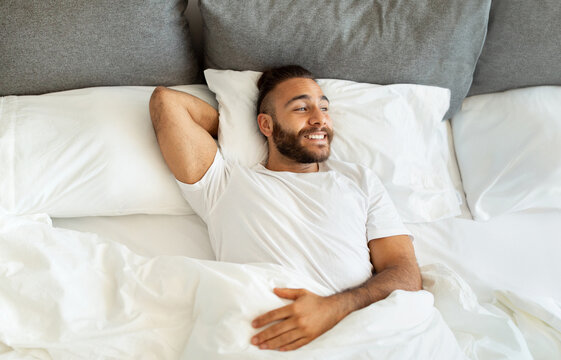 Top view cheerful bearded guy chilling in bed in morning