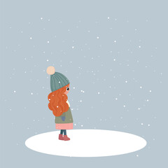 Winter picture. A girl with red hair stands under the snowfall