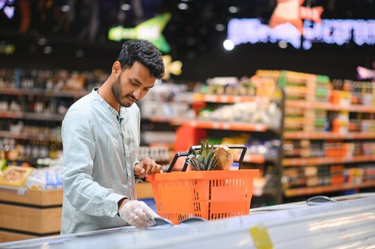 Portrait of happy handsome young Indian at grocery shop or supermarket.