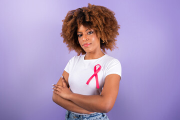 Black Woman With Pink Ribbon Over Purple Background In Studio