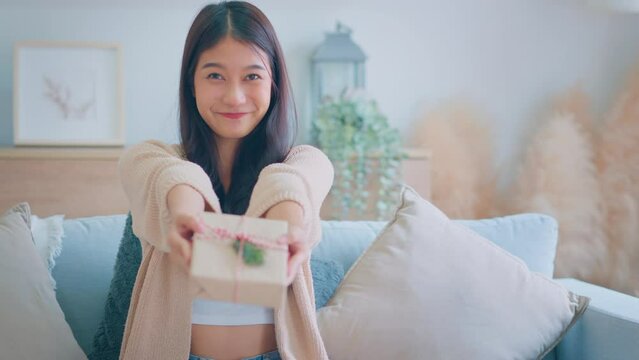 Giving a gift, Happy young asian woman giving handmade present wrapped paper. Christmas time. New Year's Eve and gift giving