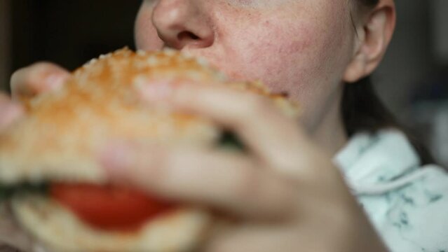 Beautiful woman eating burger in restaurant enjoying delicious juicy hamburger mouth watering meal. Close up. Slow motion.