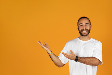 Happy millennial caucasian man with beard in white t-shirt point hands at free space