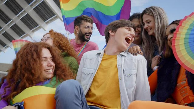 Diverse generation z people joyful group celebrating LGBT party together. Seven laughing friends from gay pride day community having fun outdoor. Lesbian, homosexual, transgender and non-binary.