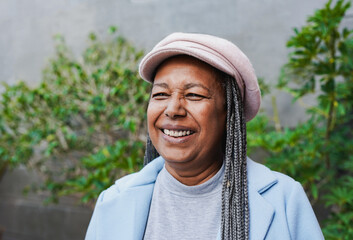 Portrait of happy senior african woman wearing trendy hat and smiling in front of camera during...