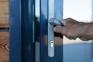 Naklejka premium male hand of an elderly person opens the door.