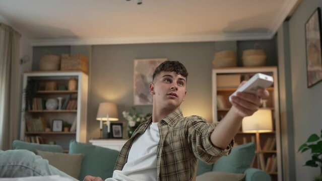 Young caucasian teenage man use remote control for TV or air-condition