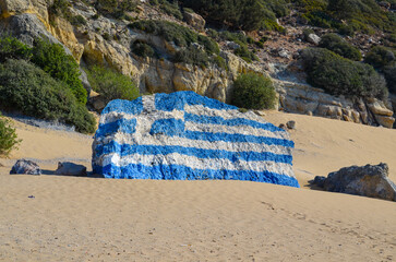 Greek flag painted on a rock. Tsambika beach on the island of Rhodes.