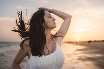 Fototapeta na wymiar portrait of beautiful woman on the beach shore with moving hair in sunset light