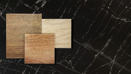 wood texture of ceramic flooring tiles samples placed on luxury dark black carrara marble stone...