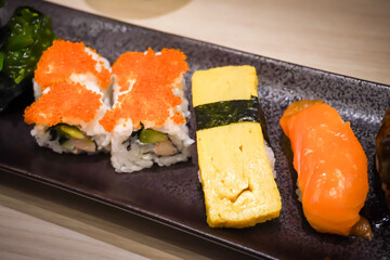 Various sushi platter in square ceramic plate on Japanese Restaurant. Concept for whole healthy food, nutrition, omega-3, animal protein, seafood, modern resto and street food. 