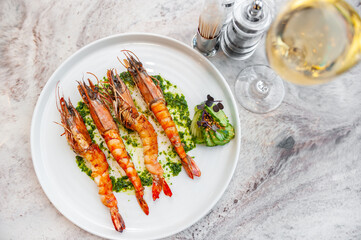 Langoustines with spinach sauce on a white plate with a glass of white wine