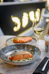 Salmon fillet in cream sauce with herbs on a marble table in a restaurant