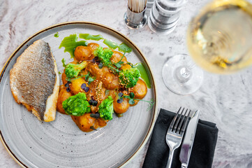 Sea bass or dorado fillet with baked potatoes and cauliflower on a gray plate