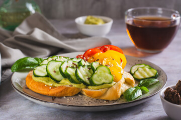 Open sandwich with avocado, cucumber, tomatoes and sesame seeds on a plate