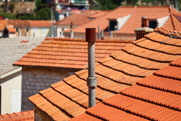 Komin na czerwonym dachu budynków widok na miasto.  - obrazy, fototapety, plakaty