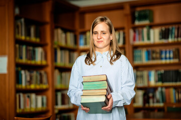 Shot of a visually impaired woman standing in the library and holding books in her hand