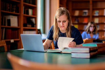 A visually impaired young woman sitting and studying in the university library