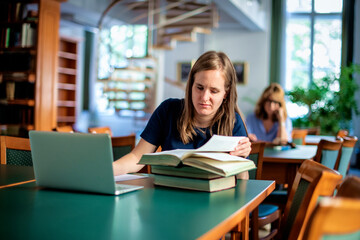 A visually impaired young woman sitting and studying in the university library