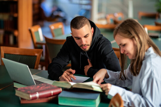 Young man supporting visaully impaired woman to study in library