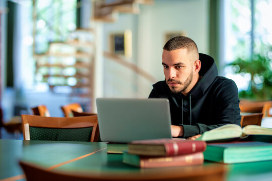 Young student using notebook and books and learning in the university library