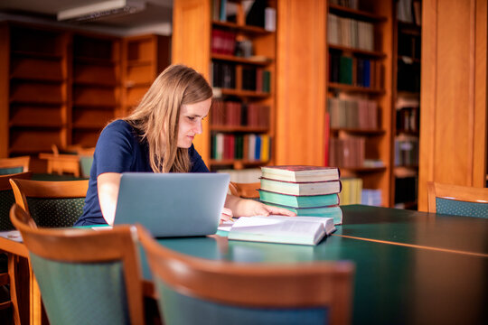 A visually impaired young woman sitting and studying in the university library
