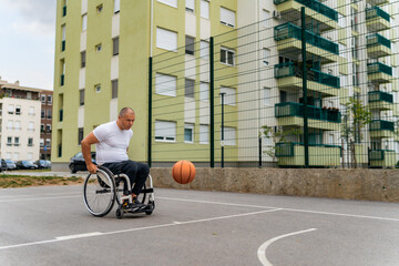 A man in a wheelchair practices free throws on a street basketball court