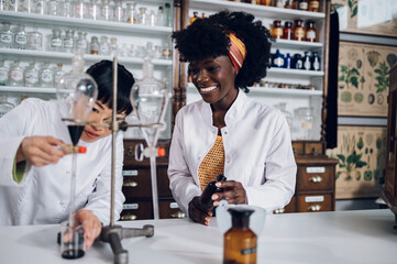 Multiracial pharmacists are standing in a vintage pharmacy and working on an experiment together.