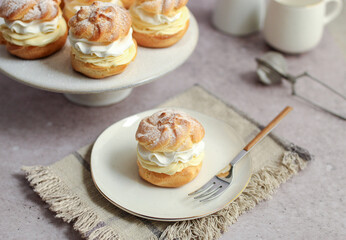 Cream puffs filled with vanilla cream and whipped cream on a white plate.