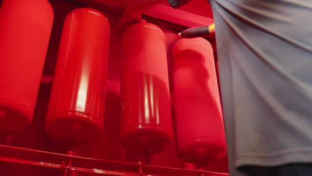 Painting factory parts with special sprayer paint. Powder coating of fire extinguishers. Painter working at industrial manufacture. Worker paints with spray gun at factory. Close-up in 4K, UHD
