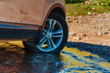 Car wheel standing offroad in a mountain creek close-up view © chaossart