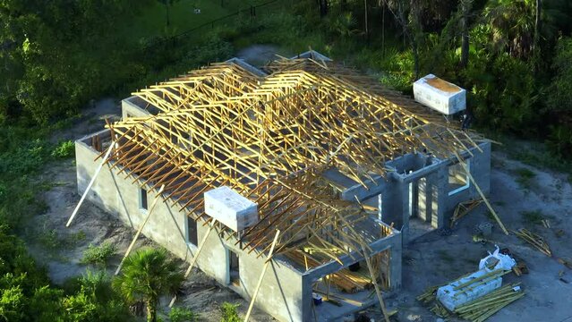 Aerial view of unfinished residential house with wooden roof frame structure under construction in Florida suburban area