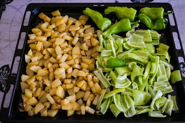 Potatoes and green peppers for frying on a baking tray