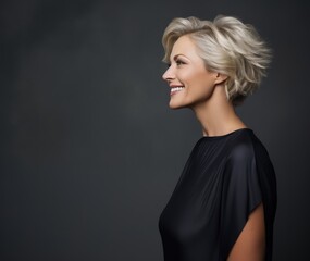 Studio portrait of a middle-aged blond smiling woman in a black blouse on a dark background. Business style.